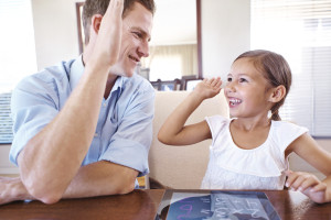 A father giving his daughter a high five after she completed a calculation on her digital tablet